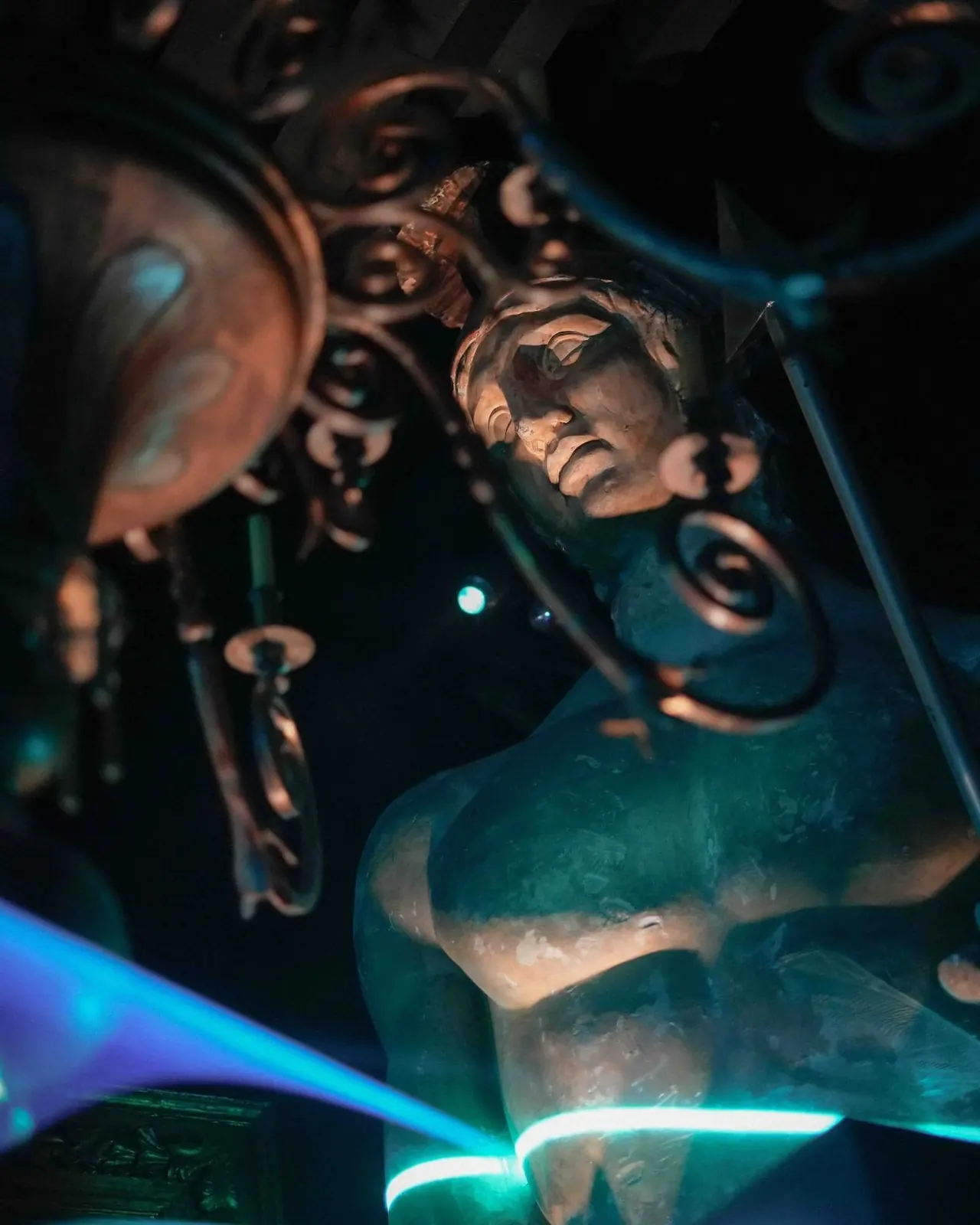 A classical statue lit by blue neon light at night